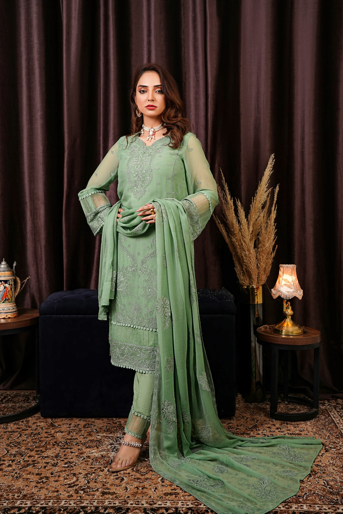 a woman in a green outfit standing in front of a curtain