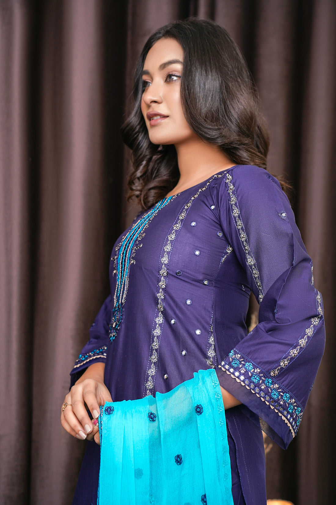 a woman in a purple dress holding a blue bag