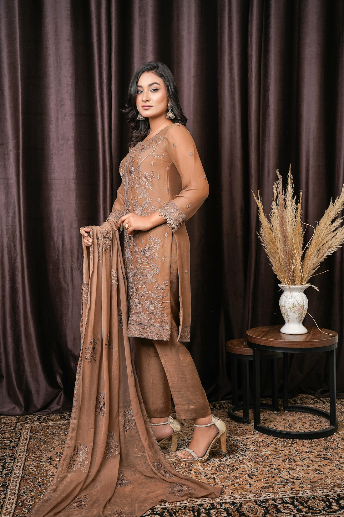 a woman standing in front of a brown curtain