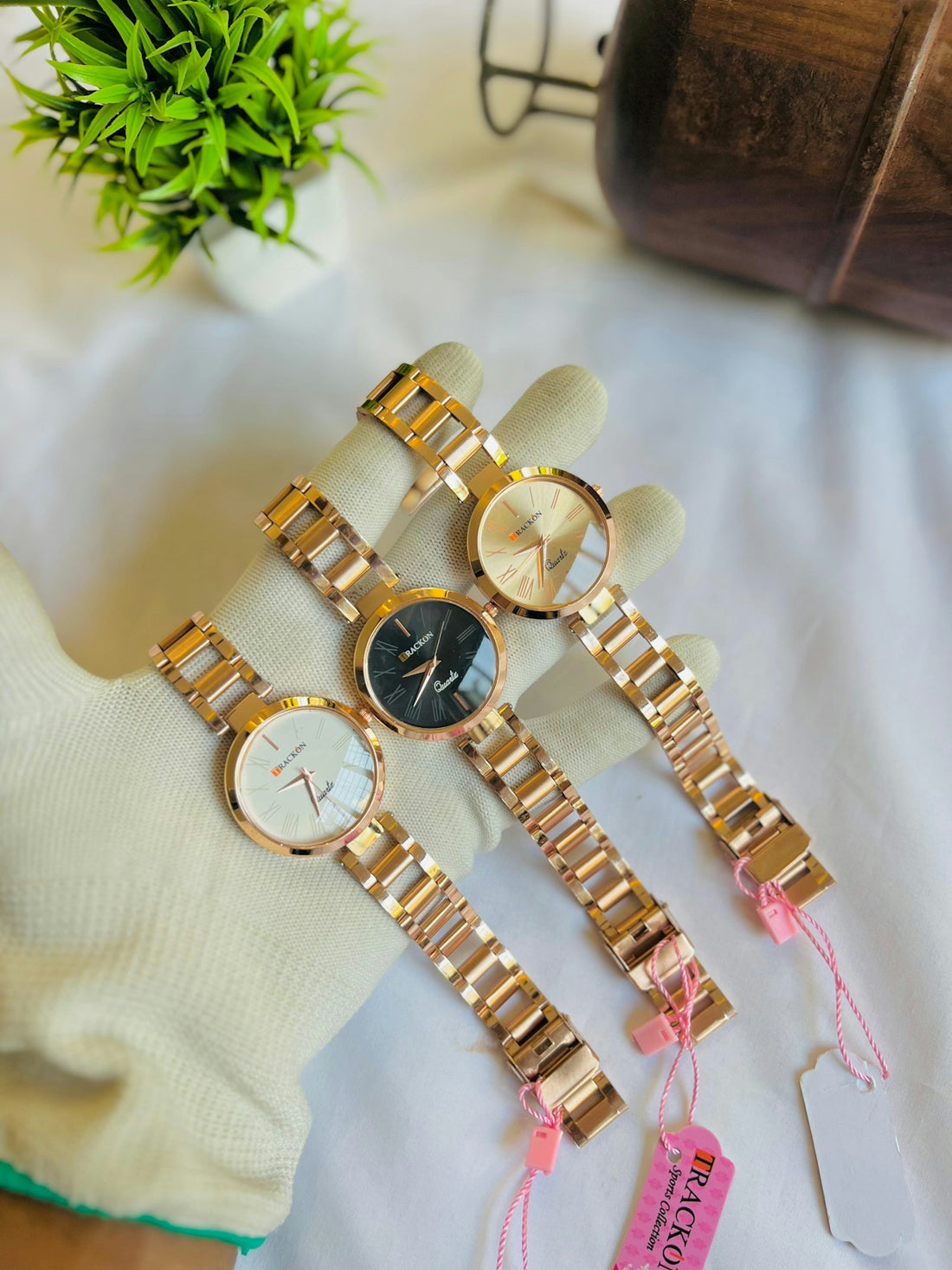 Three gold watches are presented on a white surface