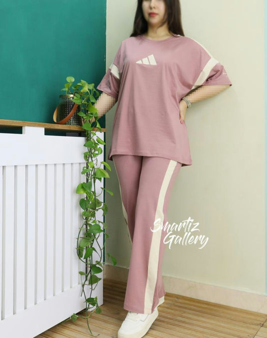 Woman wearing a pink adidas tracksuit with cream stripes.